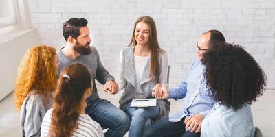 Diverse people sitting on chairs in circle holding hands photo