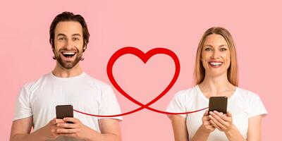 A man with a beard in an olive shirt smiles at his smartphone, and a woman with curly hair in a matching shirt looks at hers photo