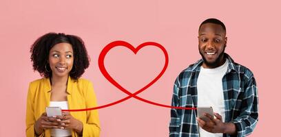 A smiling woman in a yellow blazer and a man in a plaid shirt hold smartphones, with a red heart graphic photo