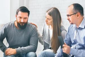 Group supporting depressed man with alcoholism problem photo