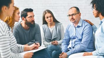 Middle-aged man sitting at support group session, telling about alcohol addiction photo