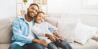 Father and daughter watching tv together at home photo