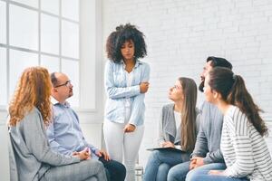 Rehab group listening to stressed woman standing up photo