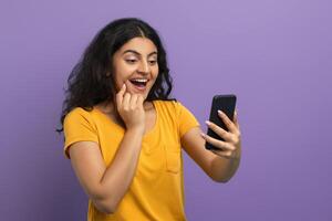Enthusiastic woman with phone on violet photo