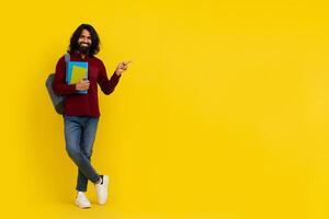 Cheerful young indian man student pointing at copy space photo