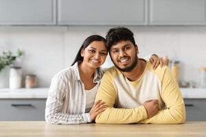 Portrait of loving young indian couple posing together at kitchen photo