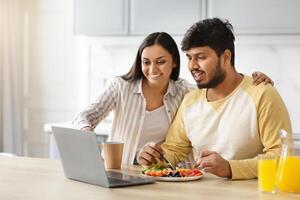 Happy eastern spouses planning vacation while have breakfast photo