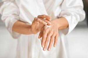 Selective focus on woman hands applying body cream photo