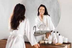 Attractive brunette long-haired millennial woman looking at mirror photo