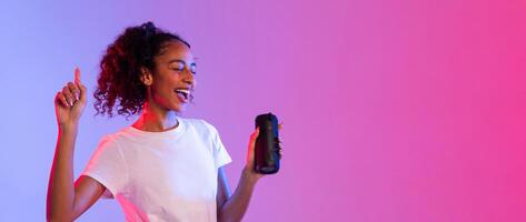 Happy black lady enjoying music with speaker on dual-tone background, panorama, free space photo