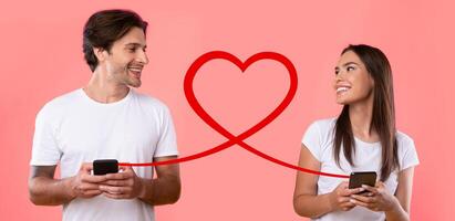 un sonriente hombre y mujer en blanco camisetas son mensajes de texto en teléfonos inteligentes, conectado por un bucle rojo corazón línea foto