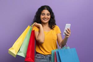 Happy shopper with colorful bags and phone photo