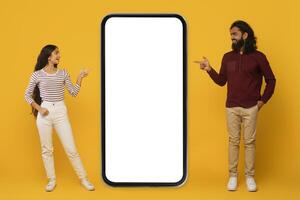 Man and woman pointing at blank phone screen on yellow photo