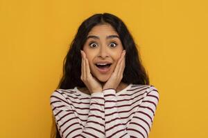 Young woman surprised expression on yellow photo