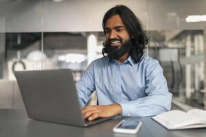 Man with a relaxed smile working on his laptop photo