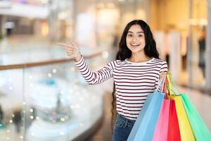 Positive young indian woman carrying purchases, copy space photo