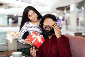 Lady giving her boyfriend birthday, anniversary gift in cozy cafe photo