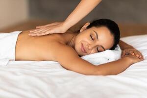 woman enjoys massage at spa while therapist rubbing her back photo