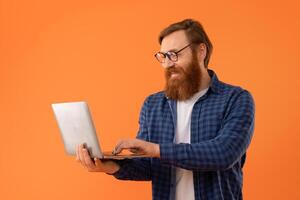 Middle aged redhaired guy with beard using laptop in studio photo