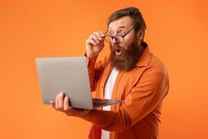 freelancer guy with beard looking at laptop touching glasses, studio photo