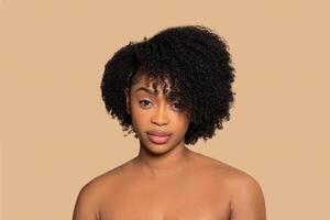 Confident black woman with bushy hair on beige backdrop photo