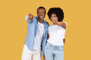 Engaging African American couple pointing directly at camera with confident smiles photo