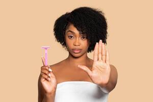 Black woman with razor says no to shaving, skincare choice photo