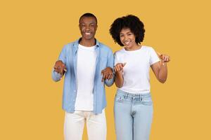 Cheerful African American couple pointing down to a blank white banner photo