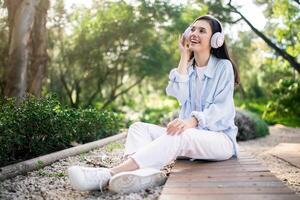 Delighted young woman with white headphones looking up and smiling photo