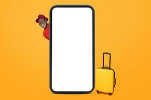 A joyful senior black man in a red sweater peeking out from behind a giant smartphone mockup photo