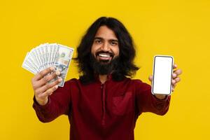 Happy eastern man showing cash and phone with blank screen photo