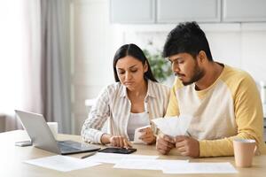 Unhappy millennial indian couple working on family budget photo