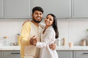 Loving young indian couple dancing in kitchen photo