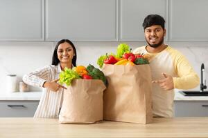 positivo joven indio Pareja señalando a tienda de comestibles pantalones foto