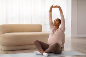 Peaceful young black pregnant woman have yoga at home photo