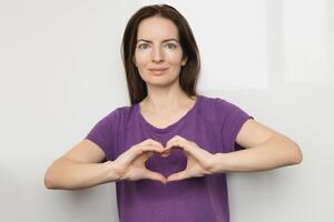 Inspire inclusion. Woman holding her hands in the shape of a heart and holding them in front of her, dressed purple t-shirt. International women's day concept. photo