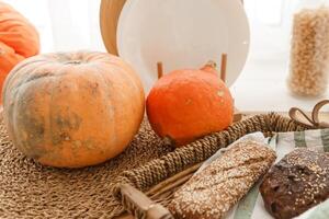 Kitchen countertop by the window in a bright room. Orange pumpkins, bread and pasta on the countertop. Autumn mood at home. photo