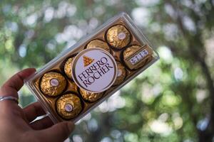 Bangkok, Thailand - March 13, 2024 Hand holds Ferrero Rocher premium chocolate photo