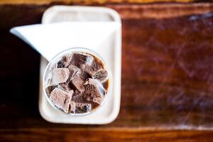 A glass of ice Mocha coffee with topping that sprinkle chocolate powder over the surface in wood table photo