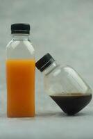 Fresco naranja jugo en un el plastico botella y negro café. foto