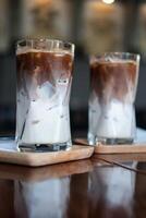 Two iced Mocha coffee two layers fresh milk and espresso short on wooden table at cafe. photo