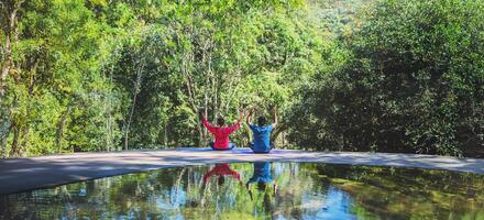 Asian woman and Asian man travel nature. Travel relax. Yoga posture concept, Good health care with yoga postures. Outdoor exercise Relax yoga. photo