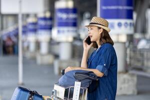 Asian woman tourist passenger is using mobile application to call pick up taxi at the airport terminal for transportation during her vacation travel and long weekend holiday photo