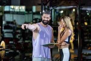 gimnasio cliente es consiguiendo Consejo y sugerencia desde su personal entrenador para hacer ejercicio plan programa y consiguiendo su evaluación gráfico desde muestra sangre prueba para su rutina de ejercicio Progreso concepto foto