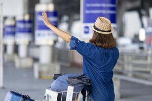 Asian woman tourist passenger is calling the pick up taxi at the airport terminal for transportation during her vacation travel and long weekend holiday photo