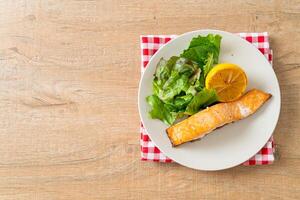 fried salmon steak with lemon and vegetable photo