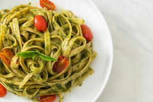 fettuccine spaghetti pasta with pesto sauce and tomatoes photo