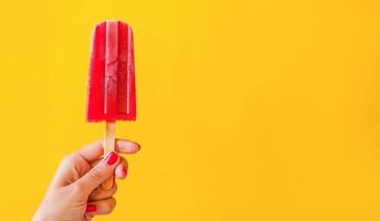 ai generado mano participación un vibrante rojo paleta de hielo en contra un brillante amarillo antecedentes foto