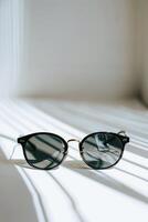 AI generated Elegant Round Sunglasses Resting on a Sunlit Surface With Dramatic Shadows photo