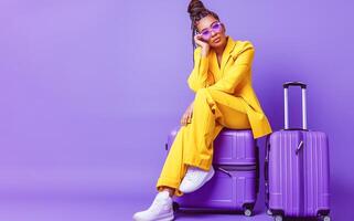AI generated Fashionable Young Woman in Vibrant Yellow Suit Sitting on Suitcase Against Purple Background photo